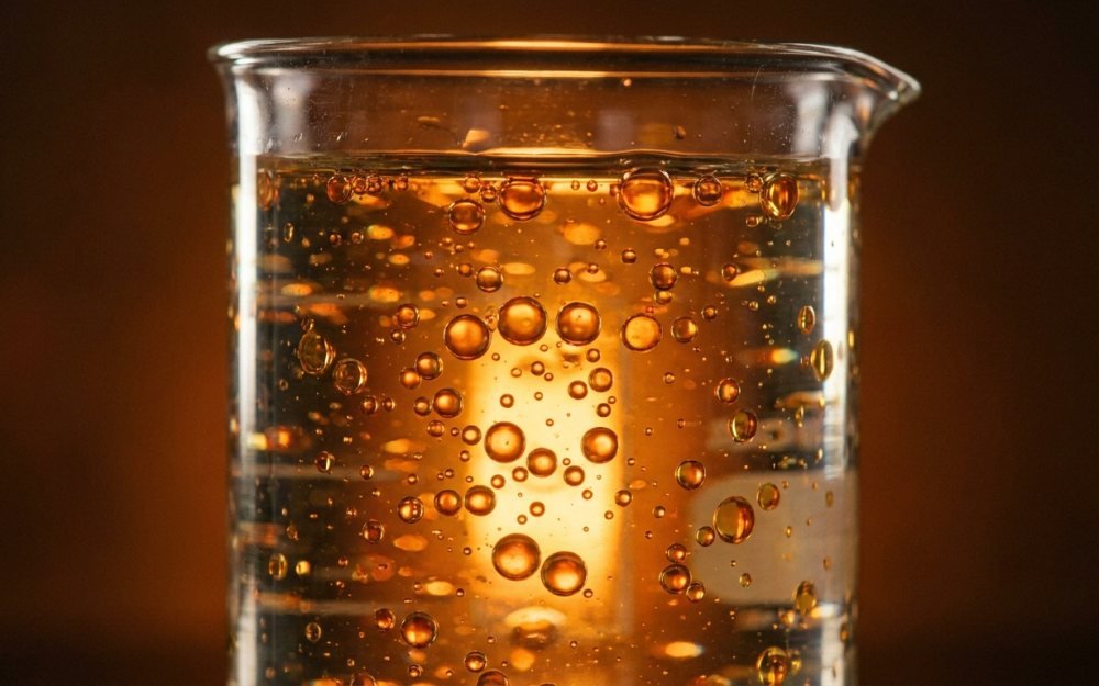 Golden droplets suspended in clear liquid, backlit